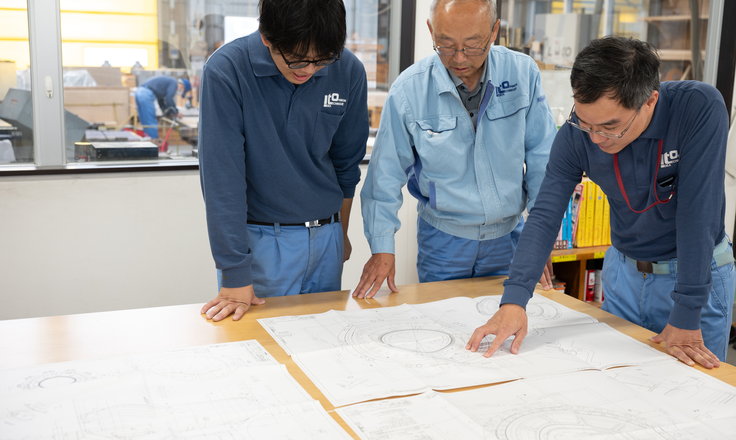 図面を囲んで工程を打ち合わせる社員