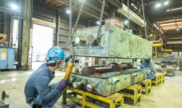 吊り上げた大型鋳型を扱う鋳造作業