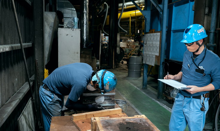 鋳造現場で作業内容を記録する社員
